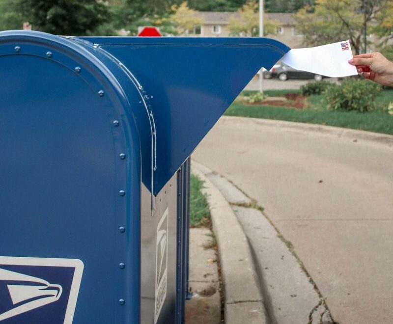 Hand inserting envelope into mailbox.