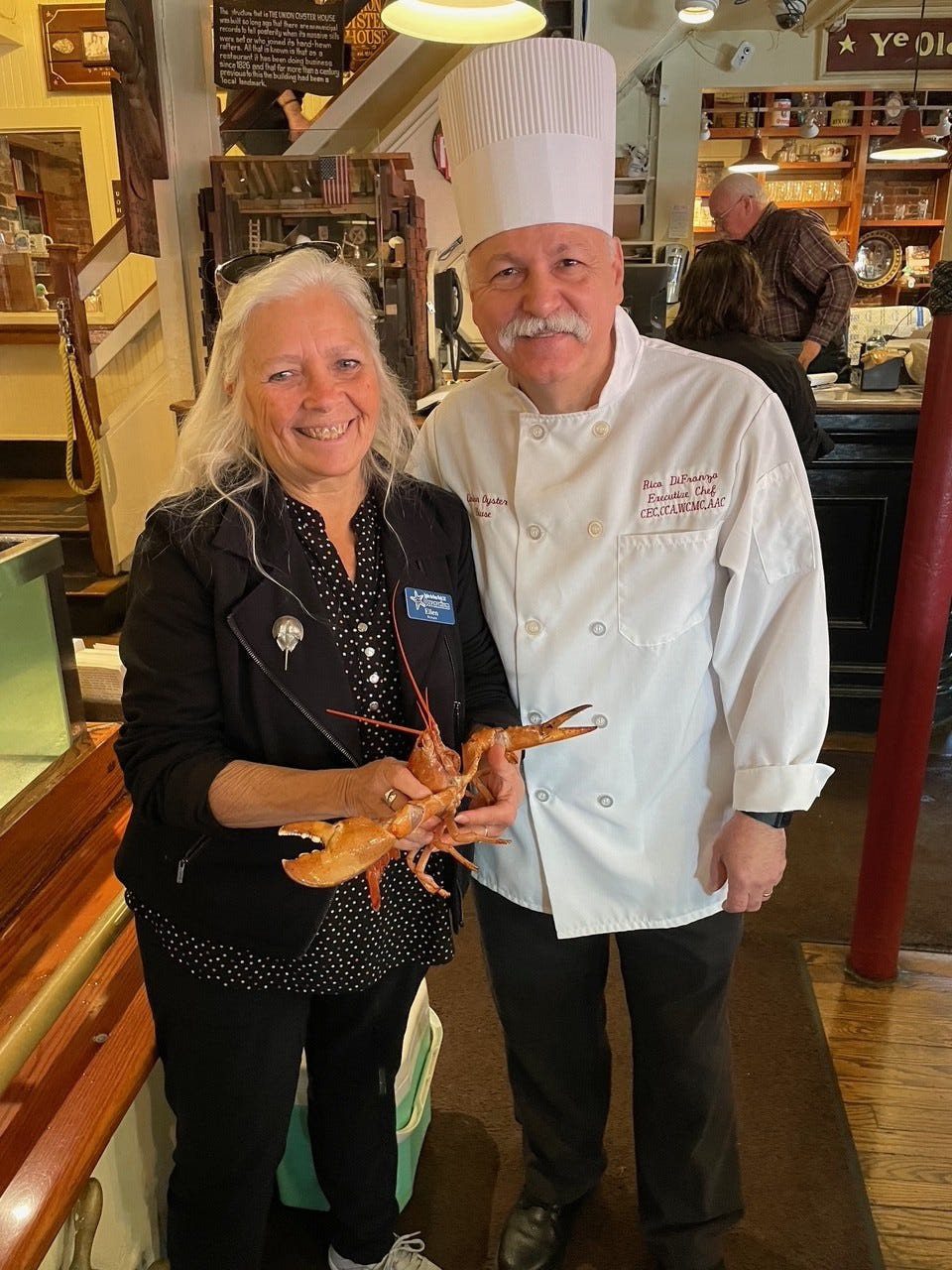 two people hold Lucky, a rare orange lobster