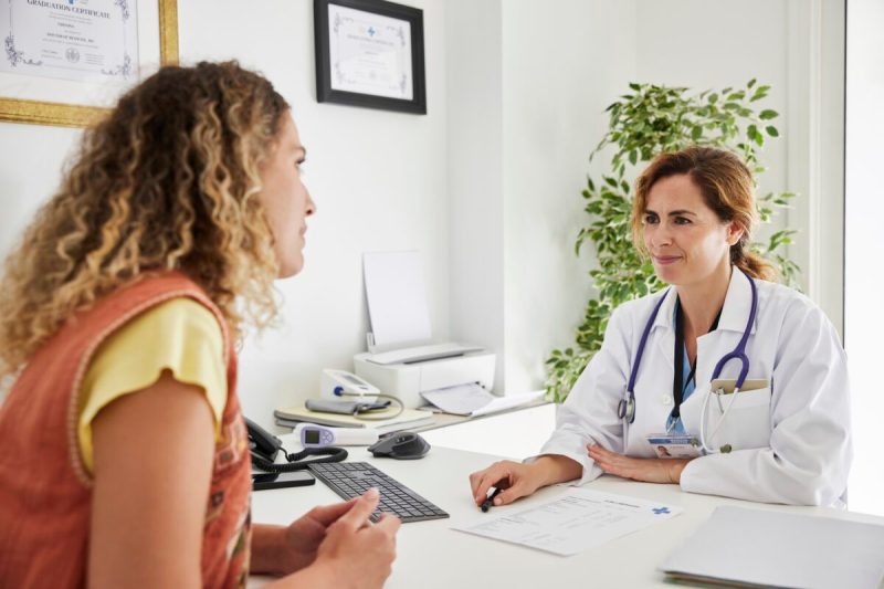 Photo of a woman patient talking to a doctor about fertility options at the desk.